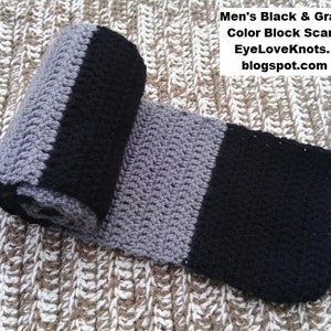 May include: A black and gray crocheted scarf with a color block design. The scarf is rolled up and photographed on a textured surface. EyeLoveKnots.blogspot.com