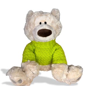May include: A plush teddy bear with a light beige fur and a bright green knitted sweater. The bear has a brown snout and black button eyes. The bear is sitting with its legs extended.