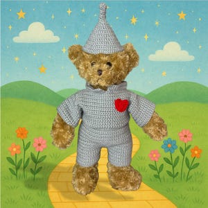 Può includere: Un orsacchiotto di peluche vestito con un completo grigio all'uncinetto, con un cappello abbinato e un cuore rosso sul petto. L'orso è su una strada di mattoni gialli con uno sfondo di colline verdi, nuvole e stelle.