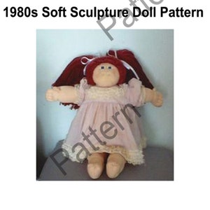 Op de afbeelding: Een zachte sculptuurpop uit de jaren 1980, met een rond gezicht en rood haar. De pop draagt een roze jurk met kanten rand. De tekst "1980s Soft Sculpture Doll Pattern" staat bovenaan de afbeelding.