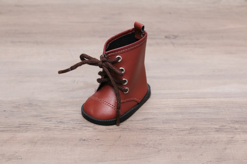 May include: A pair of brown leather lace-up boots with black laces. The boots have a rounded toe and a low heel.