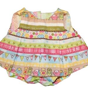 Pode incluir: Um conjunto de beb&eacute; colorido com um top e cuecas a condizer. O conjunto tem uma saia plissada e &eacute; decorado com riscas, bolinhas e ilustra&ccedil;&otilde;es de corujas. O texto "Owl you need is love" est&aacute; impresso no tecido.