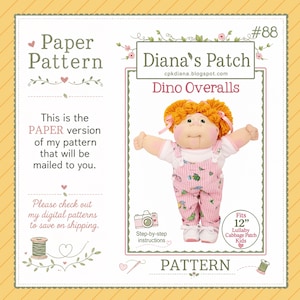 May include: A paper pattern for Dino Overalls by Diana's Patch, featuring a doll with orange yarn hair wearing pink striped overalls with dinosaur prints. The document includes text, a camera icon, and states it fits 12-inch Lullaby Cabbage Patch Kids.
