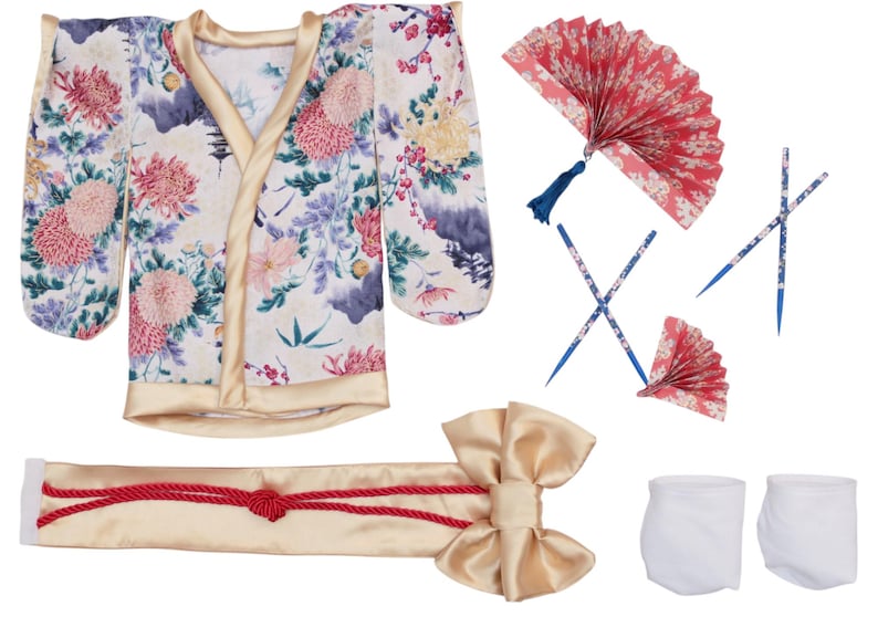 Op de afbeelding: Een Japanse kostuumset met een kimono met bloemenpatroon en gouden rand, een bijpassende obi-riem met een strik, twee waaiers, eetstokjes en witte sokken. De kimono heeft een cr&egrave;mekleurige achtergrond met roze, paarse en groene bloemmotieven.