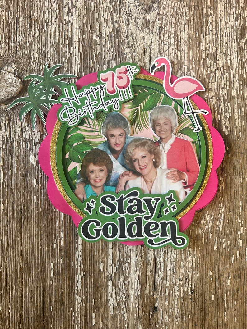 May include: A pink and green cake topper with a photo of four women and the text "Happy 75th Birthday!! Stay Golden".