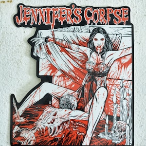 May include: A black and white illustration of a woman in a white dress lying on a bed with a bloody scene. The text "JENNIFER'S CORPSE" is at the top of the image.
