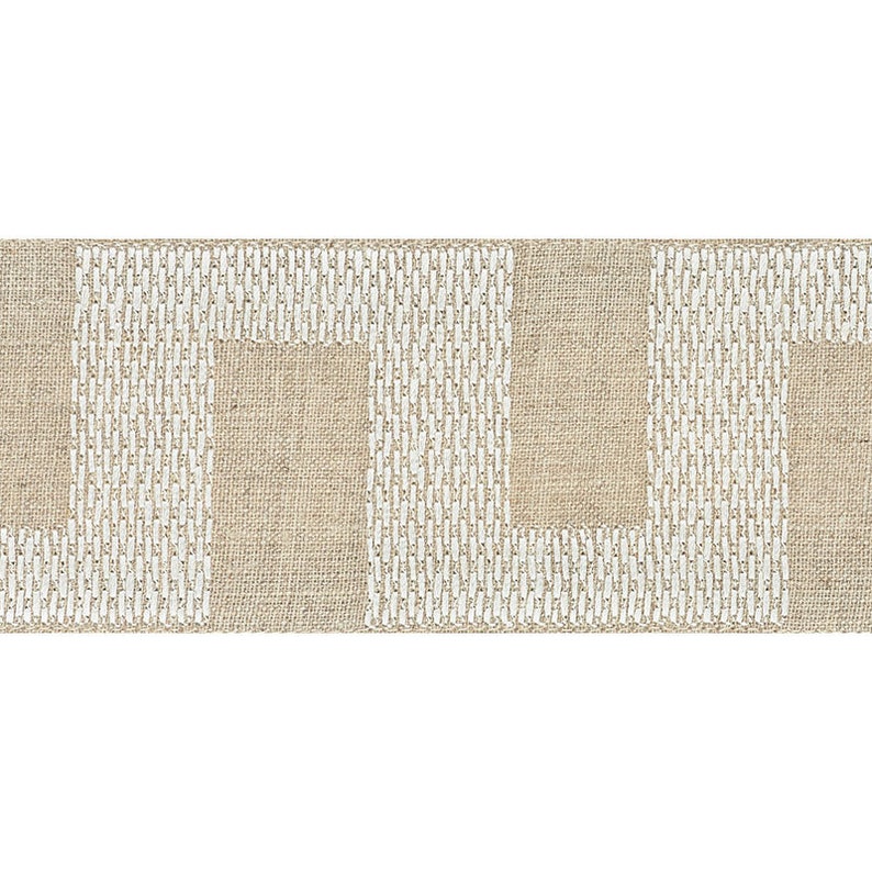 May include: A beige fabric with a white geometric pattern. The pattern is made up of repeating squares and rectangles.
