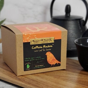 May include: A brown cardboard box with a label that says "Because UR Pricekas" and "Caffeine Machine Loose Leaf Tea Sampler". The label also features a small bird illustration and the text "Visit Us Online becauseurpriceless.com".