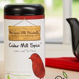 May include: A red and white tin of loose leaf tea blend called "Cider Mill Spice" with a red bird illustration. The tin is labeled "Because UR Priceless" and "Organic Ingredients".