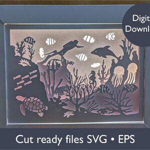 May include: A framed, layered paper art piece depicting an underwater scene. The design features a diver, fish, coral, a sea turtle, and jellyfish. The text "Digital Download" and "Cut ready files SVG • EPS" are also included.