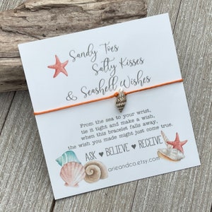 May include: Orange string bracelet with a seashell charm and a card that reads "Sandy Toes Salty Kisses & Seashell Wishes". The card also includes the text "From the sea to your wrist, tie it tight and make a wish, when this bracelet falls away, the wish you made might just come true. ASK BELIEVE RECEIVE arieandco.etsy.com".
