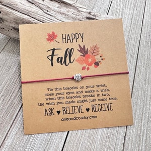 May include: A red string bracelet with a silver leaf charm and a card that says "HAPPY Fall" with fall-themed illustrations. The card also includes the text: "Tie this bracelet on your wrist, close your eyes and make a wish, when this bracelet breaks in two, the wish you made might just come true. ASK BELIEVE RECEIVE arieandco.etsy.com"
