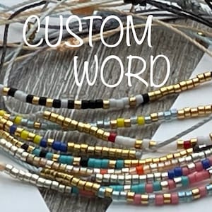 May include: A close-up of several colorful beaded bracelets with gold accents. The bracelets are layered on top of each other and the text "CUSTOM WORD" is visible in the background.
