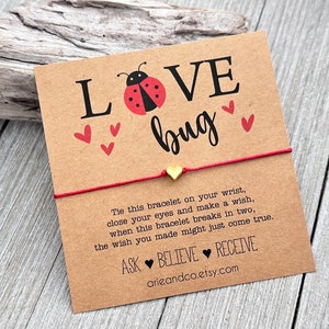 May include: Red string bracelet with a gold heart charm and a card that says "LOVE bug" with a ladybug illustration and the text "Tie this bracelet on your wrist, close your eyes and make a wish, when this bracelet breaks in two, the wish you made might just come true. ASK BELIEVE RECEIVE arieandco.etsy.com"