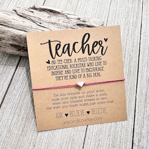 May include: A pink and white friendship bracelet with a silver heart charm. The card reads "Teacher (N) TEE-CHER: A MULTI-TASKING EDUCATIONAL ROCKSTAR WHO LIVE TO INSPIRE AND LOVE TO ENCOURAGE THEY'RE KIND OF A BIG DEAL. Tie this bracelet on your wrist, close your eyes and make a wish, when this bracelet breaks in two, the wish you made might just come true. ASK BELIEVE RECEIVE arieandco.etsy.com"