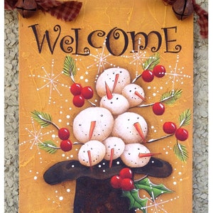 May include: A hand-painted wooden sign with a whimsical winter scene. The sign features a black top hat with a group of snowmen wearing red berries and green holly. The sign reads "Welcome Winter Snowballs" and includes the artist's signature and website.