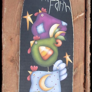 May include: A black painted wooden sign with the text "Prim Chick's Punkin' Farm" in white paint. The sign features three cartoon chickens stacked on top of each other, with a pumpkin at the bottom. The chickens are purple, green, and blue with white polka dots. The pumpkin is orange with a green stem and a smiling face.