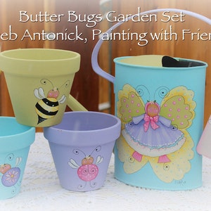 Puede incluir: Un conjunto de tres macetas de terracota pintadas con una regadera. Las macetas están decoradas con una abeja, una mariquita y una mariposa. La regadera está pintada con una mariposa y el texto "Butter Bugs Garden Set © Deb Antonick, Painting with Friends".