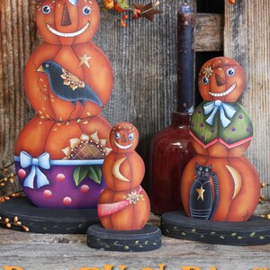 May include: Three painted pumpkin figures with smiling faces, wearing hats and holding a bird, a cat, and a crescent moon. The pumpkins are on black bases with green vines. The text "PUMPKIN PALS" is at the top of the image. The text "Copyright Deb Antonick WWW.PAINTINGWITHDEB.COM" is at the bottom of the image. The text "From My Book "A Touch of Primsey" is below the copyright information.