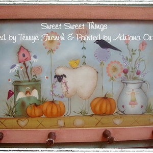 Può includere: Un dipinto incorniciato intitolato "Sweet Sweet Things" disegnato da Terrye French e dipinto da Adriana Ortolano. Il dipinto presenta una pecora bianca con il naso nero, un uccello, una casetta per uccelli, fiori, zucche e un vaso con fiori.