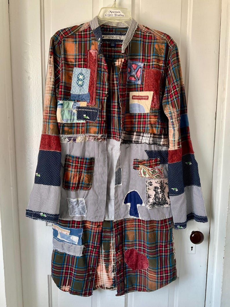 May include: A long-sleeved button-down shirt featuring a patchwork design of red, green, and blue plaid fabric mixed with white and black pinstriped panels. The garment is adorned with various fabric patches, including a blue mushroom and a dog.