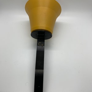 May include: A gold-colored handbell with a black handle. The handle has the text "C5" printed on it.