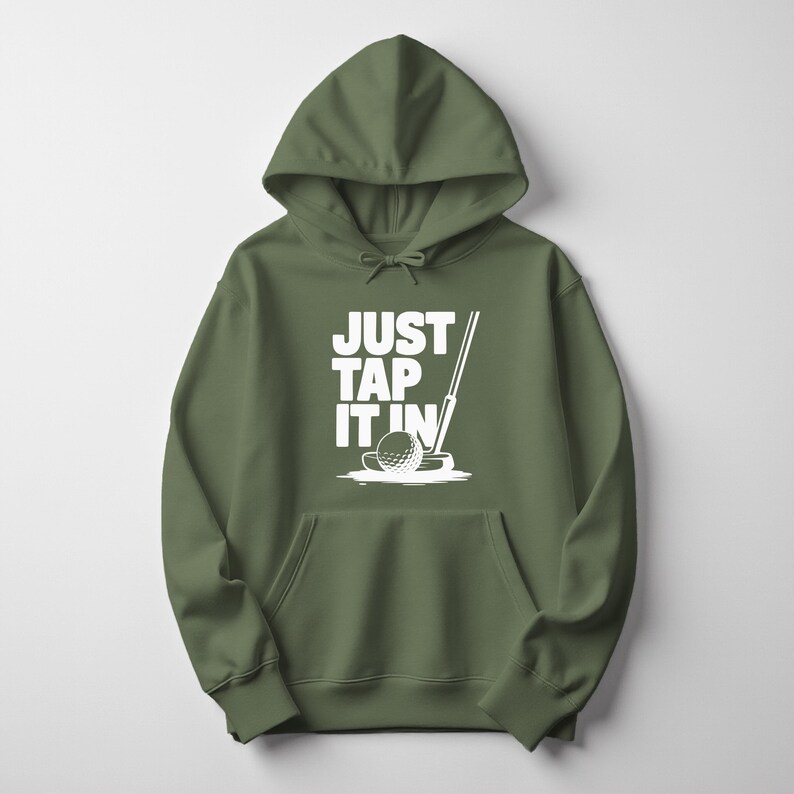 Puede incluir: Sudadera con capucha verde oliva con un gr&aacute;fico blanco de una pelota de golf, un palo y el texto "JUST TAP IT IN". La sudadera tiene una capucha con cord&oacute;n y un bolsillo delantero. Una prenda casual y c&oacute;moda para los golfistas.