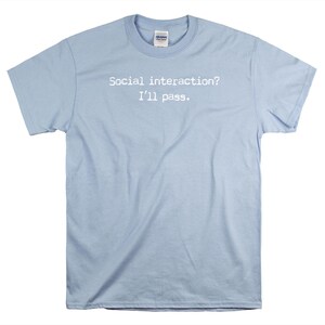 May include: Light blue t-shirt with the text "Social interaction? I'll pass." printed in white.