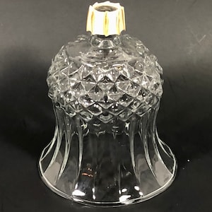 May include: Clear glass candle holder with a diamond pattern on the top and a flared base. The top has a decorative gold and white accent. The candle holder is designed to hold a small candle and is suitable for home decor.