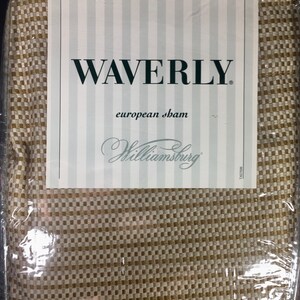 May include: A Waverly European sham in a tan and white checkered pattern, enclosed in clear plastic packaging. The product label features the text WAVERLY, european sham, and Williamsburg, with a vertical striped background design.