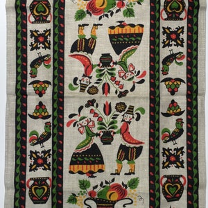May include: Linen tea towel with a folk art design. The towel features a central panel with figures, flowers, and fruit baskets, framed by a black, red, and green border. The bottom right corner has a label that reads "All Pure Linen".