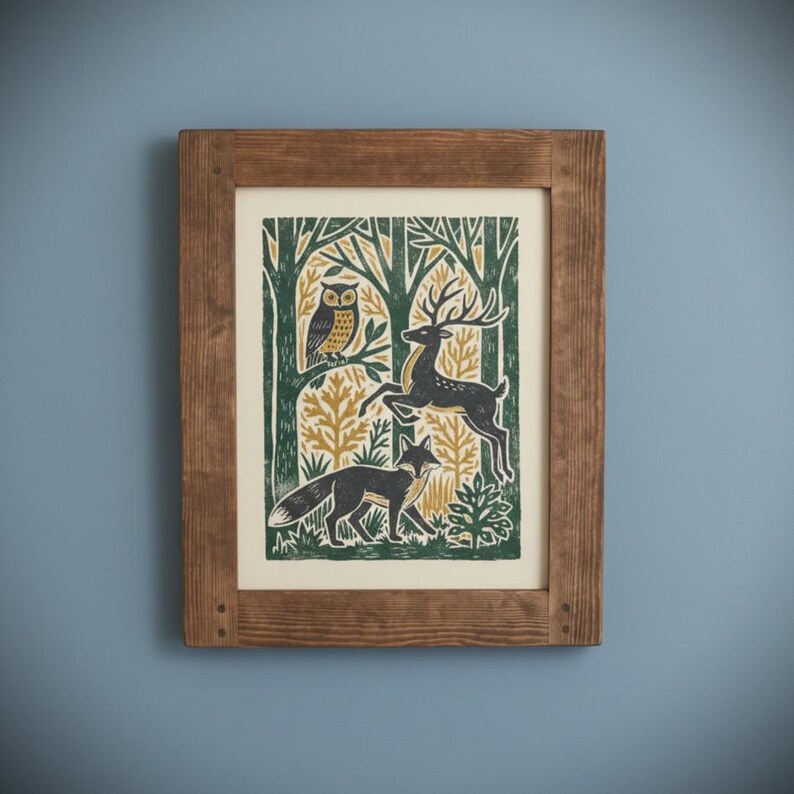 May include: A framed art print featuring a forest scene with an owl, deer, and fox. The print has a green, gold, and black color scheme. The frame is made of wood and has a natural finish. The artwork is mounted on a cream-colored background.