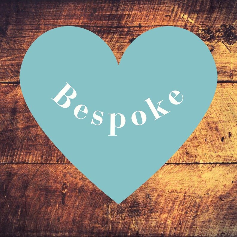 May include: A light blue heart shape with the word "Bespoke" in white script. The heart is set against a rustic, wooden background with visible grain and warm brown tones.