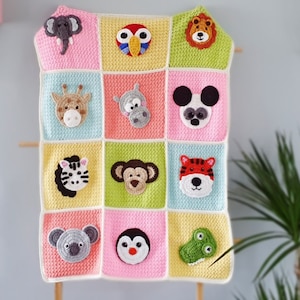 Pode incluir: Uma manta de bebé feita à mão em croché com doze quadrados coloridos, cada um exibindo uma cara de animal diferente, incluindo um elefante, papagaio, leão, girafa, hipopótamo, panda, zebra, macaco, tigre, koala, pinguim e um crocodilo verde.