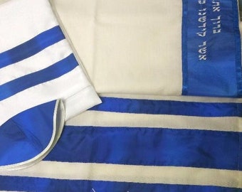 Puede incluir: Un chal de oración blanco y azul con rayas y ribetes azules. El chal tiene forma rectangular con un gorro a juego azul y blanco. El ribete azul tiene texto hebreo. El chal está hecho de una tela suave y ligera.
