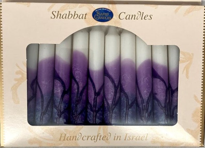 Puede incluir: Una caja de velas de Shabat de color morado y blanco con el texto "Shabbat Candles" y "Handcrafted in Israel".