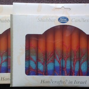 Puede incluir: Una caja de velas de Shabat de color naranja y azul con el texto "Shabbat Candles" y "Handcrafted in Israel".