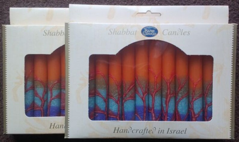 Puede incluir: Una caja de velas de Shabat de color naranja y azul con el texto "Shabbat Candles" y "Handcrafted in Israel".
