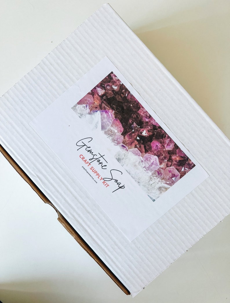 May include: White cardboard box with a label that says "Gemstone Soap Craft Supply Kit" and a picture of purple and pink gemstones.