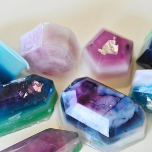 May include: A collection of colorful, geometrically shaped soaps with a translucent, marbled appearance. Some soaps have silver flakes embedded in them.