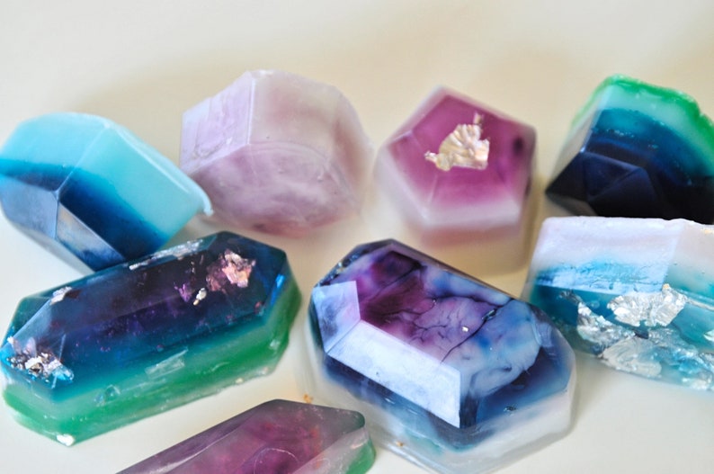 May include: A collection of colorful, geometrically shaped soaps with a translucent, marbled appearance. Some soaps have silver flakes embedded in them.