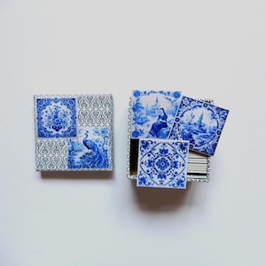 Può includere: Due scatole quadrate con piastrelle in ceramica blu e bianca. Una scatola presenta un motivo a pavone, l'altra varie scene blu e bianche. Le piastrelle sono disposte in modo decorativo, mostrando un'estetica classica di Delftware.