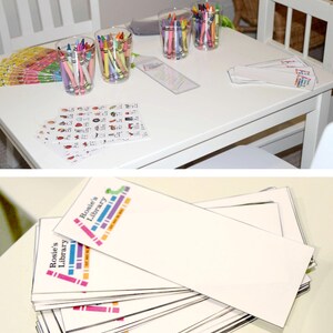 May include: A white table with a stack of colorful bookmarks that say "Rosie's Library" and a set of crayons in clear cups.