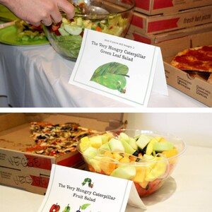 May include: Two bowls of salad with signs that say "The Very Hungry Caterpillar Green Leaf Salad" and "The Very Hungry Caterpillar Fruit Salad".