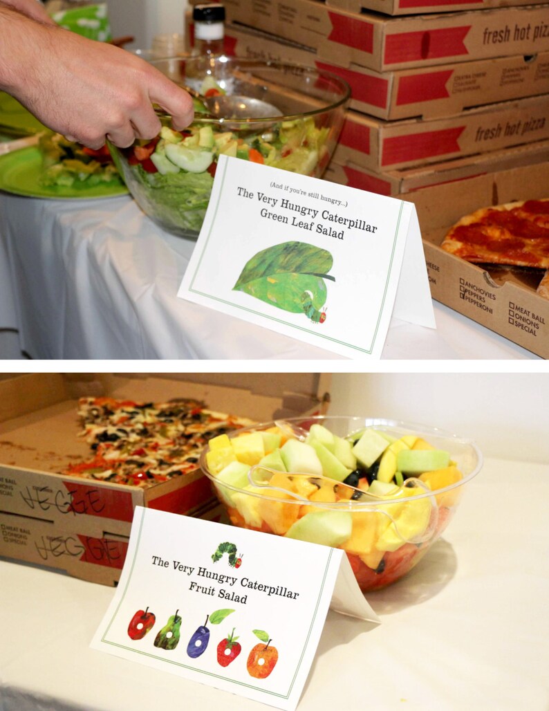 May include: Two bowls of salad with signs that say "The Very Hungry Caterpillar Green Leaf Salad" and "The Very Hungry Caterpillar Fruit Salad".
