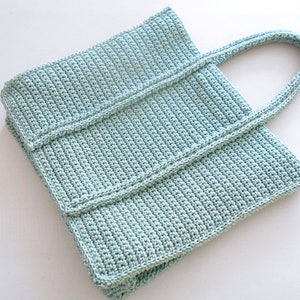 Op de afbeelding: Een lichtblauwe gehaakte tote bag met twee handvatten. De tas is gemaakt met een eenvoudig steekpatroon en heeft een rechthoekige vorm.