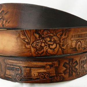May include: A brown leather belt with a firefighter theme. The belt is decorated with embossed images of firefighters, fire trucks, and flames. The belt also has the text "Firefighter" and the years "1930" and "1970" embossed on it.
