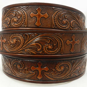 Może przedstawiać: Trzy brązowe skórzane paski z wytłoczonym wzorem krzyża i kwiatów.