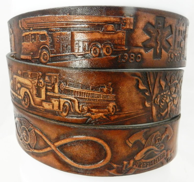 May include: Three brown leather belts with embossed designs. The top belt features a fire truck, the middle belt features a fire truck and firefighters, and the bottom belt features a fire hose, an axe, and the word "Firefighter".