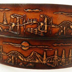 May include: Two brown leather belts with an embossed design of a western landscape with oil derricks, mountains, and a moon.